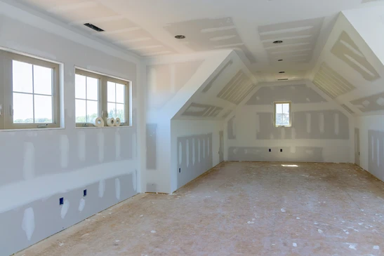 Intérieur en cours de finition avec murs en plaques de plâtre fraîchement posées, prêts pour peinture